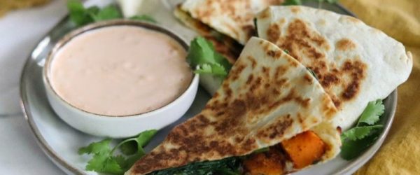Four Wedges of a Butternut Squash, Spinach & Cheese Quesadilla on Plate with Parsley and a Shallow, Round Bowl of Chipotle Cream Sauce
