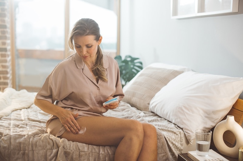 A Woman Applies Cream to Her Thigh, Representing Cellulite Treatment.