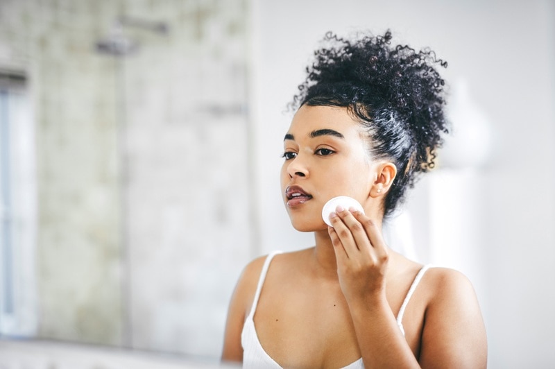 A Woman Uses a Chemical Exfoliant on Her Face With a Cotton Pad.
