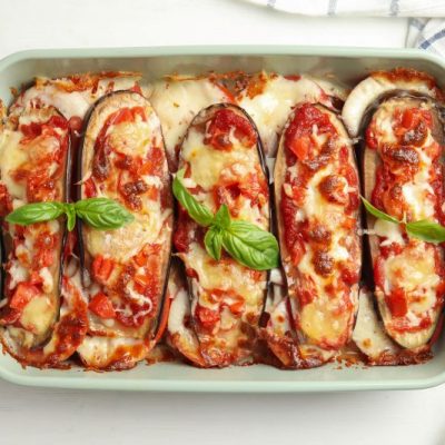 Cheesy, Bubbly Eggplant Pizza Boats in Rectangular Ceramic Baking Dish, Basil Leaves Scattered About on Top