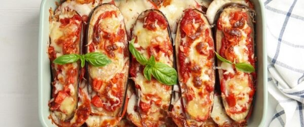 Cheesy, Bubbly Eggplant Pizza Boats in Rectangular Ceramic Baking Dish, Basil Leaves Scattered About on Top