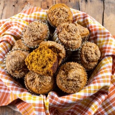 Gluten-Free Pumpkin Muffins with Sugar Sprinkles on Top in Linen Napkin-Lined Basket on Wood Table