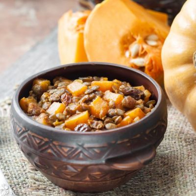 Butternut Squash Lentil Chili in Artistic Round Bowl on Burlap Placemat Next to Whole and Cut Up Squash