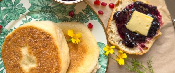 Homemade English Muffins on Fine China. A Sliced Muffin is Slathered with Butter and Jam.
