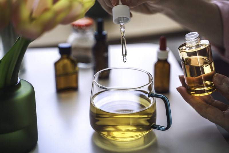 Person Using Dropper to Dispense Herbal Extracts into Mug of Tea