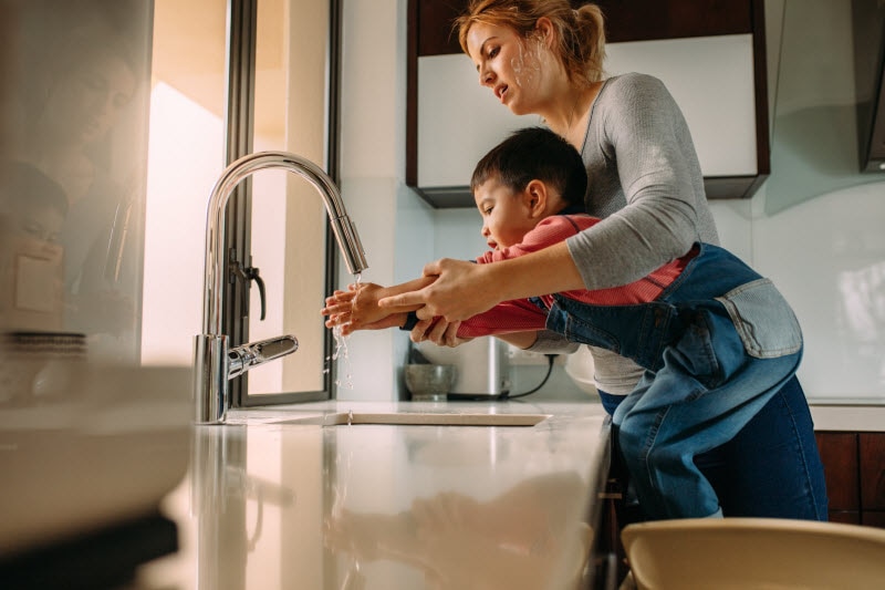 Mother Helping Child Wash Hands to Represent How o Prevent Getting Sick Concept