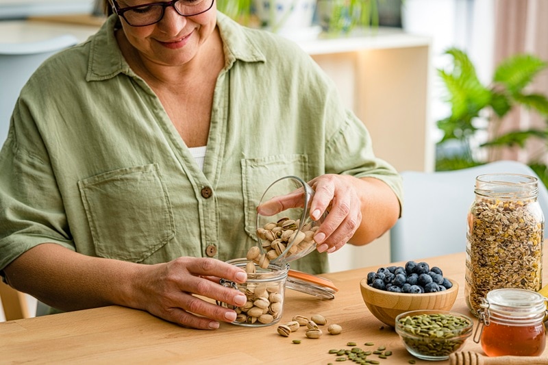 A Woman Prepares Low Carb Snacks for Diabetes, Including Nuts.