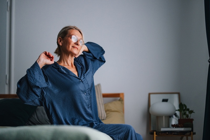An Older Woman Wakes Up Looking Happy and Refreshed, Representing Someone Who No Longer Experiences Menopause Night Sweats.
