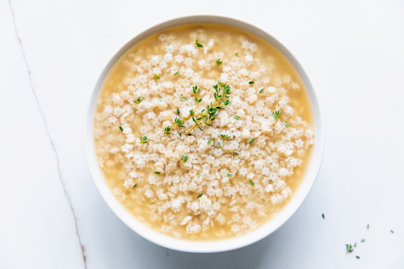 Stelline Soup with Star Pasta and Thyme Sprigs in Round Bowl on Marble Counter