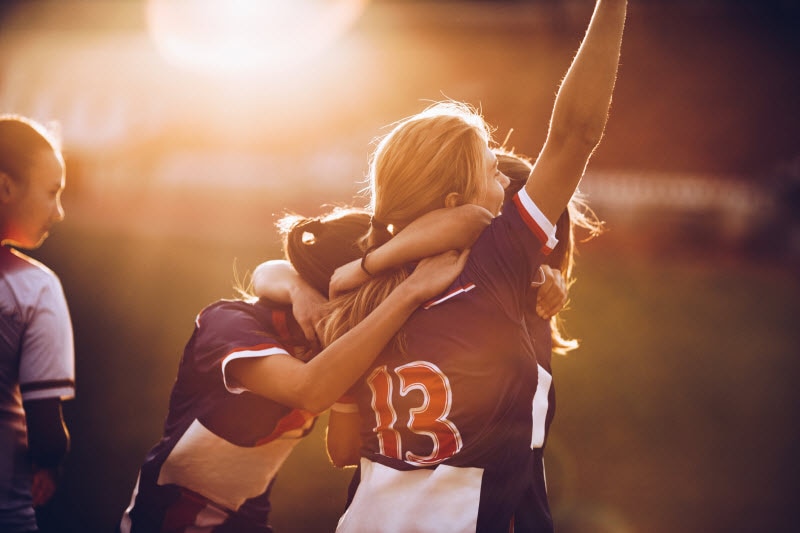 Women's Sports Concept Represented by Teen Girl Athletes Celebrating Victory on Playing Field