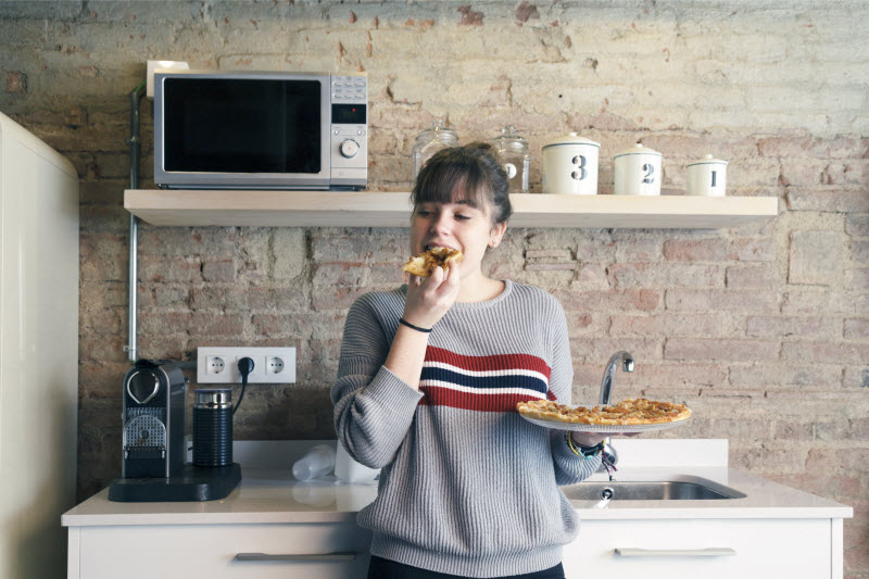 Concept of Prediabetes in Kids Represented by Teen Girl Eating Pizza in Kitchen