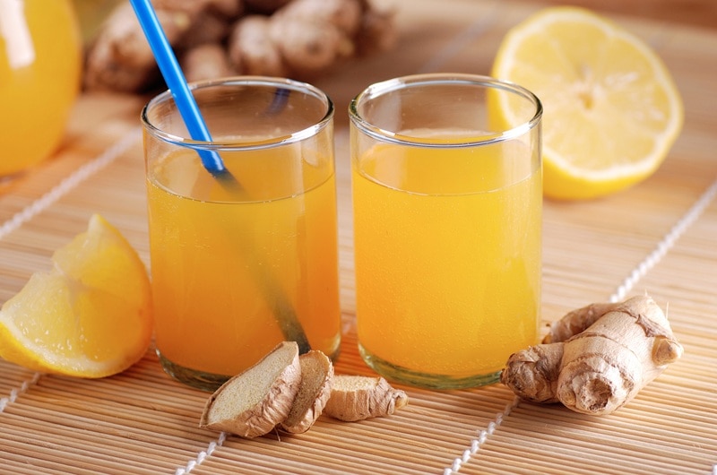 Two Glasses Are Filled With a Cortisol Cocktail and Are Surrounded by Fresh Ginger and Sliced Lemon, Representing the Question, "What is a Cortisol Cocktail?"