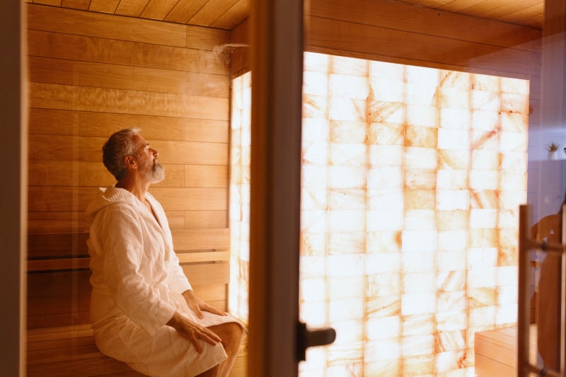 5 Proven Benefits of Saunas for Your Body and Mind Relaxed-Looking Bearded Man in White Bath Robe Enjoying the Health Benefits of Saunas