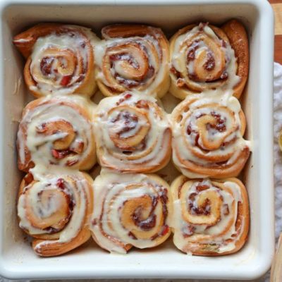 Glazed Apple Cinnamon Rolls in Square Baking Dish on Table Strewn with Apples and Lemons