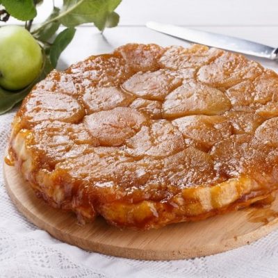 Caramel Apple Upside Down Cake on Wooden Board with Golden Caramelized Apple Topping and Fresh Green Apple in Background