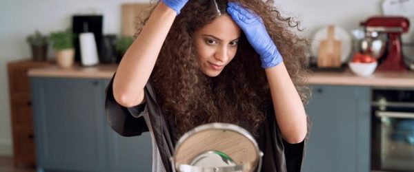 Best Natural Hair Dye Woman Applying Natural Hair Dye at Home in Front of Mirror While Wearing Blue Gloves