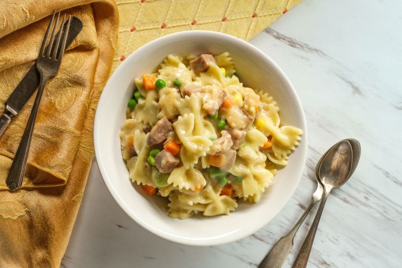 Big Bowl of Chicken Pot Pie Made with Bow-Tie Pasta in Round Bowl on Marble Counter