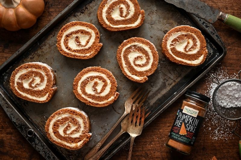 Classic Pumpkin Roll Slices with Cream Cheese Filling on Baking Sheet with Frontier Co-Op Pumpkin Pie Spice and Vintage Forks