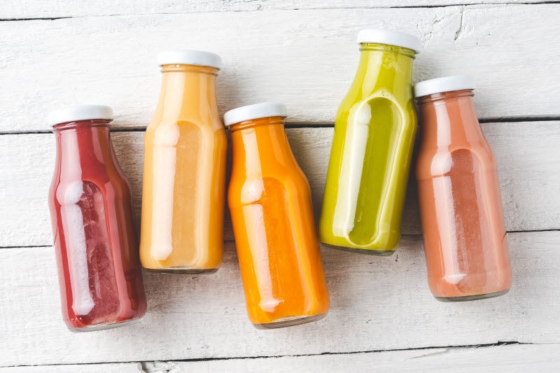 Flat Lay Overhead View of 5 Bottles of Colorful Functional Beverages on White Wood Surface