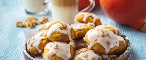 Plate Of Brown Butter Cookies With Pumpkin And Icing On A Blue Wooden Table, Topped With Cinnamon And Served Beside Glasses Of Creamy Coffee And Fresh Pumpkins