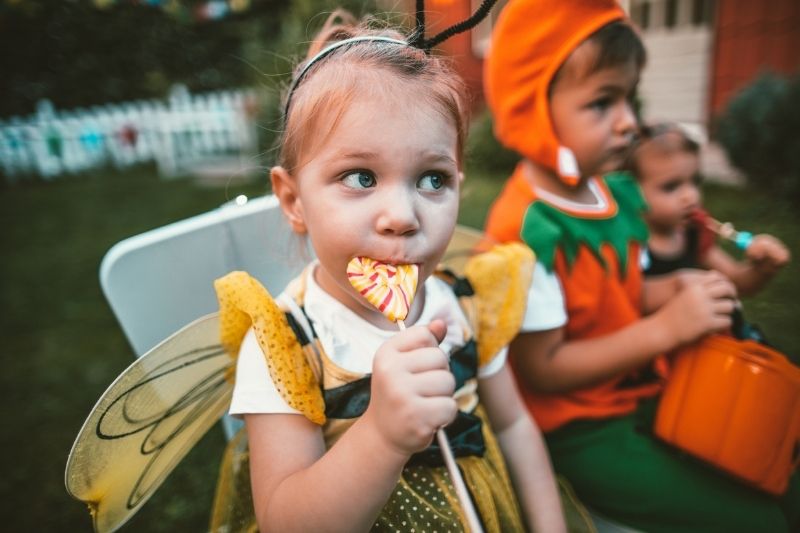 Little Girl in Bee Costume Enjoying Halloween Treat Ideas With Crowd of Kids