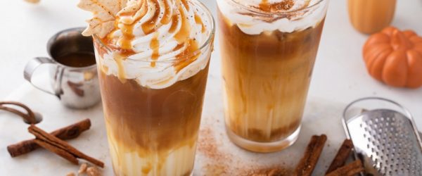 Two Iced Pumpkin Caramel Lattes Are Topped With Whipped Cream, Caramel Drizzle and Little Leaf Cookies.