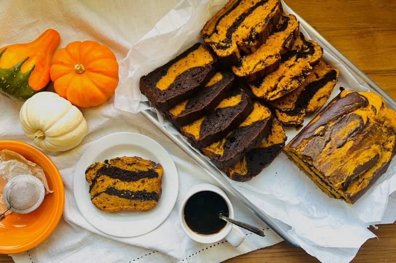 Pumpkin-Chocolate Marble Loaf Cake Sliced on Baking Tray with Coffee and Mini Pumpkins
