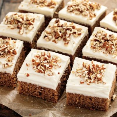 Sliced Squares of Pumpkin Sheet Cake with Creamy Frosting and Chopped Nuts on Top