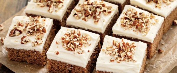 Sliced Squares of Pumpkin Sheet Cake with Creamy Frosting and Chopped Nuts on Top