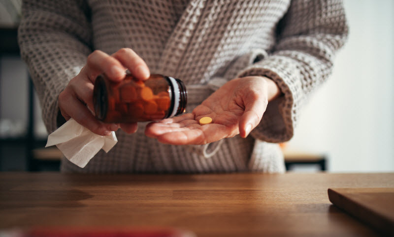 What are Methylated Vitamins - And Why Consider Them Woman Pouring Capsules From Bottle of Supplements Into Hand to Represent Concept of What are Methylated Vitamins