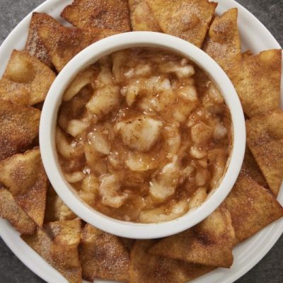 Cinnamon-Sprinkled Apple Salsa in a Round Bowl Set in the Middle of a Round Serving Plate Arrayed With Cinnamon Chips