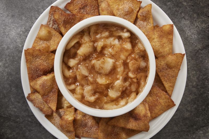 Cinnamon-Sprinkled Apple Salsa in a Round Bowl Set in the Middle of a Round Serving Plate Arrayed With Cinnamon Chips