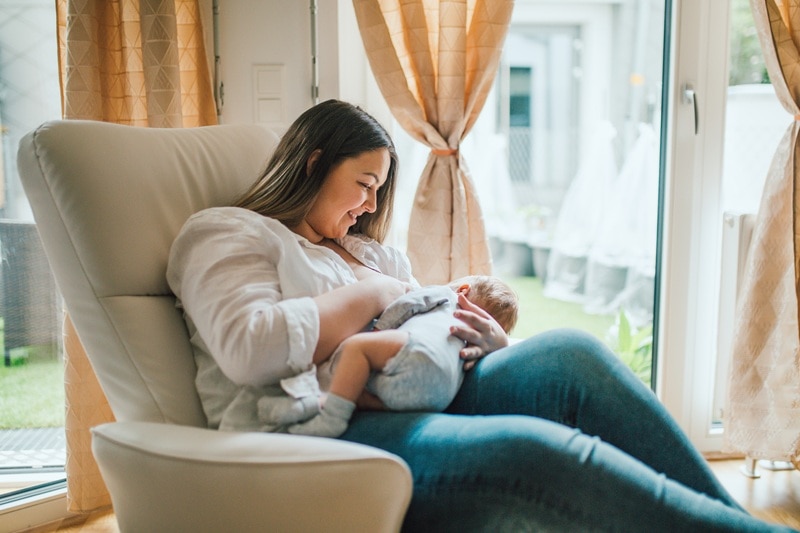 A Mother Smiles as She Breastfeeds Her Baby, Representing Breastfeeding Tips.