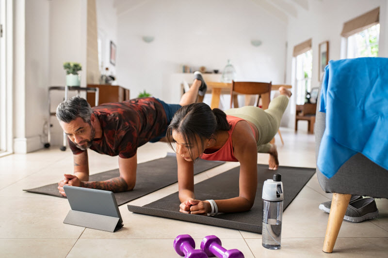 Concept of Does Exercise Prevent Cancer Represented by Active Couple Doing Online Workout in Living Room