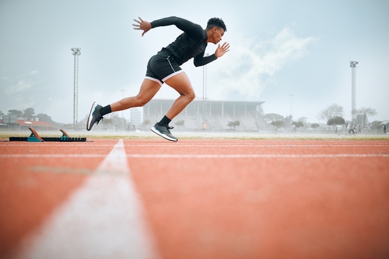 A Man Sprints on a Track, Representing Endurance vs Stamina.