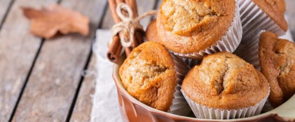 Fresh-Milled Banana Pumpkin Muffins in Rustic Crock-Type Bowl on an Outdoor Wooden Table with Fallen Leaves