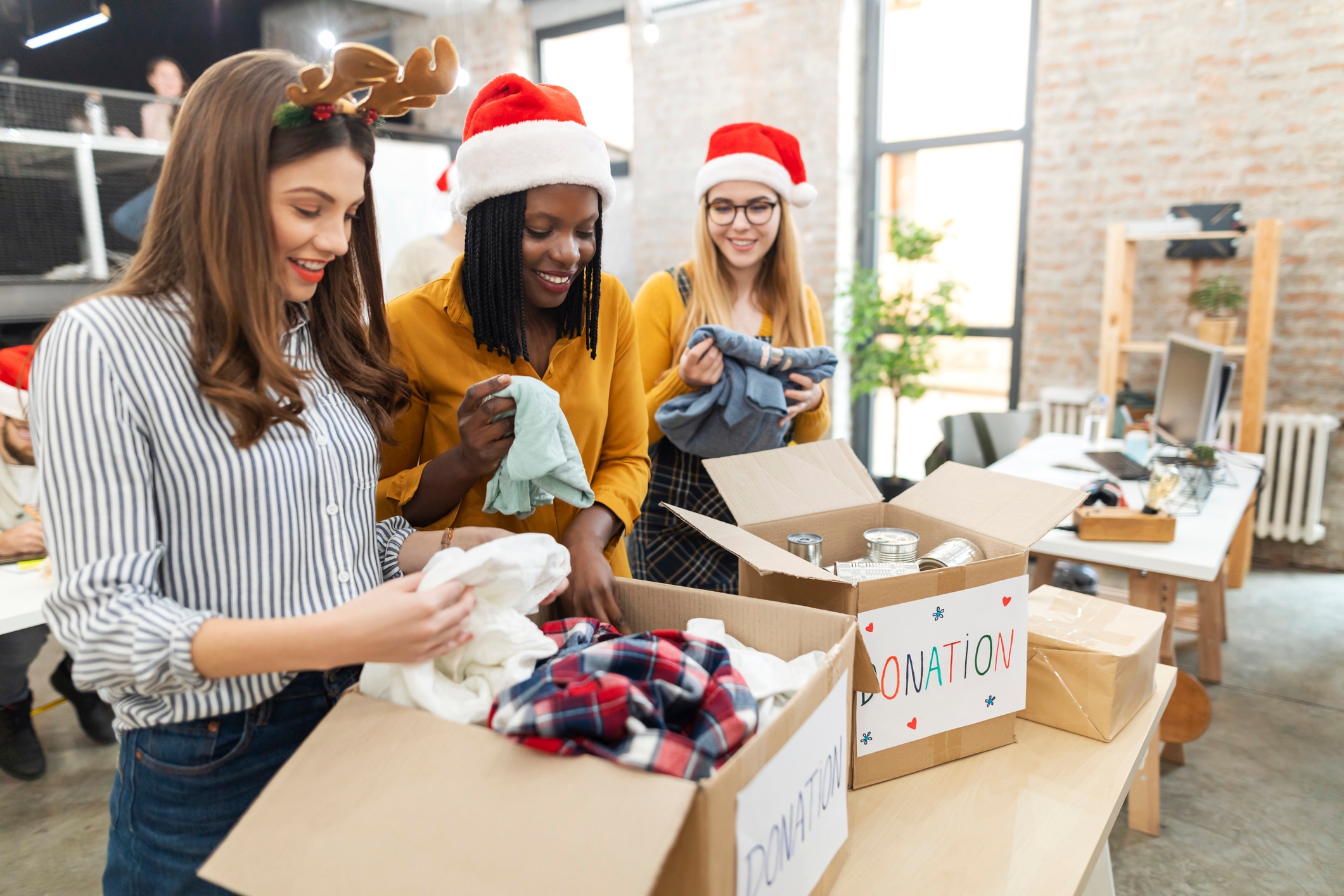 Three young colleagues, celebrating Christmas on work and collecting donations.
