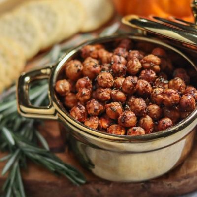 Roasted Rosemary-Infused Crispy Chickpeas in Metal Serving Pot on Charcuterie Board with Crackers, Veggies and Rosemary Sprigs