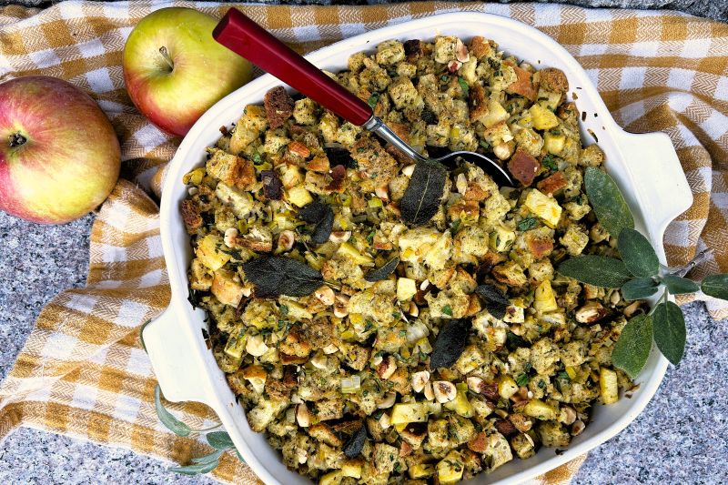 Sage Brown Butter & Apple Stuffing in Oven Pan on Granite Counter with Linen Kitchen Towel and Whole Apples