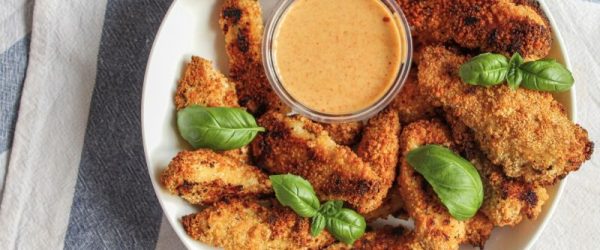 Golden-Brown Baked and Breaded Turkey Nuggets on a Serving Plate With a Dish of Dipping Sauce