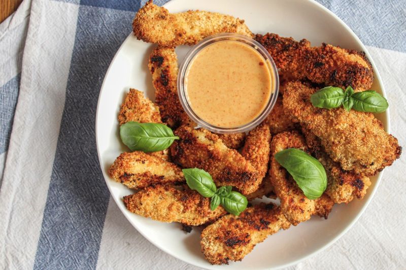 Golden-Brown Baked and Breaded Turkey Nuggets on a Serving Plate With a Dish of Dipping Sauce