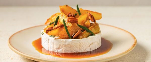 A Wheel of Brie on a Plate With Caramelized Pears & Toasted Walnuts all Nestled in a Pool of Caramelized Sugar