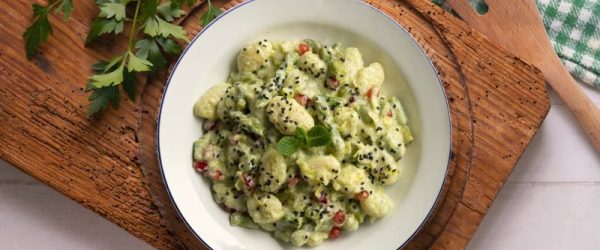 Gnocchi in Yogurt-Asparagus Cream Sauce Dotted with Pomegranate Arils on Bowl on Wooden Tray