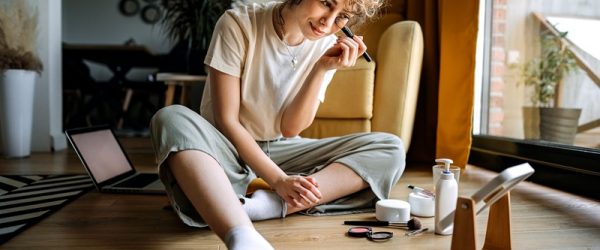 Makeup Trends 2025 A Young Woman Applies Makeup While Sitting on Her Bedroom Floor, Representing Makeup Trends 2025.