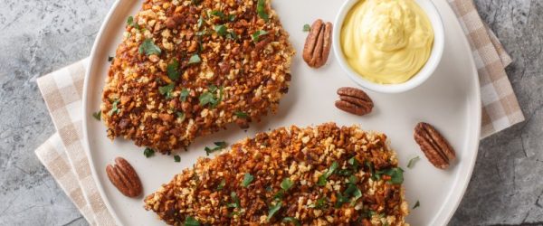 Pecan-Crusted Chicken_Resized Image_Liana Werner-Gary Pecan-Crusted Chicken Breast Sprinkled with Chopped Parsley on a Plate with a Bowl of Honey Mustard Sauce