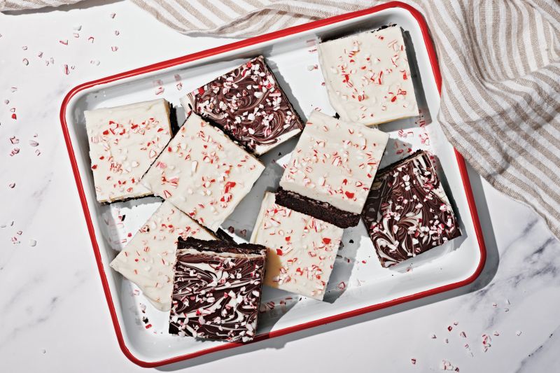 Brownies Topped with Swirled Chocolate Bark Dotted with Crushed Peppermint Candies in White Enamel Pan with Red Rim