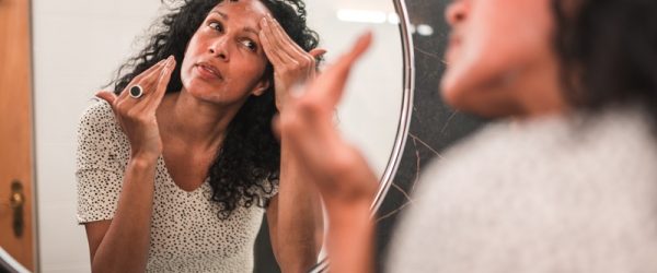A Perimenopausal Woman Applies Face Cream, Representing Perimenopause Skin Changes and Products That Help.