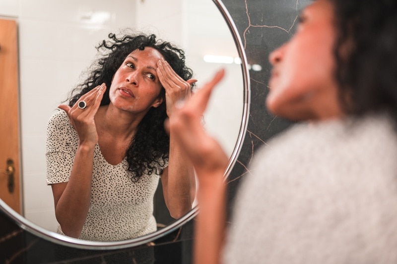 A Perimenopausal Woman Applies Face Cream, Representing Perimenopause Skin Changes and Products That Help.