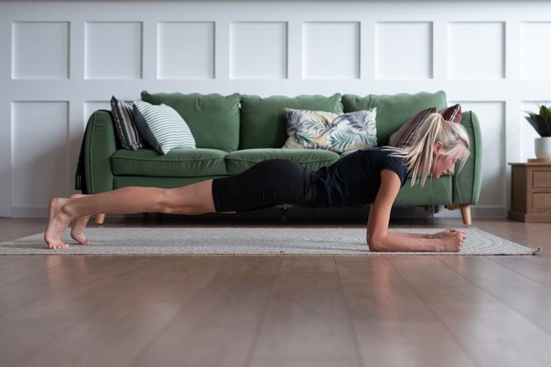 A Woman Performs a Plank on Her Living Room Floor, Representing Posture Exercises.