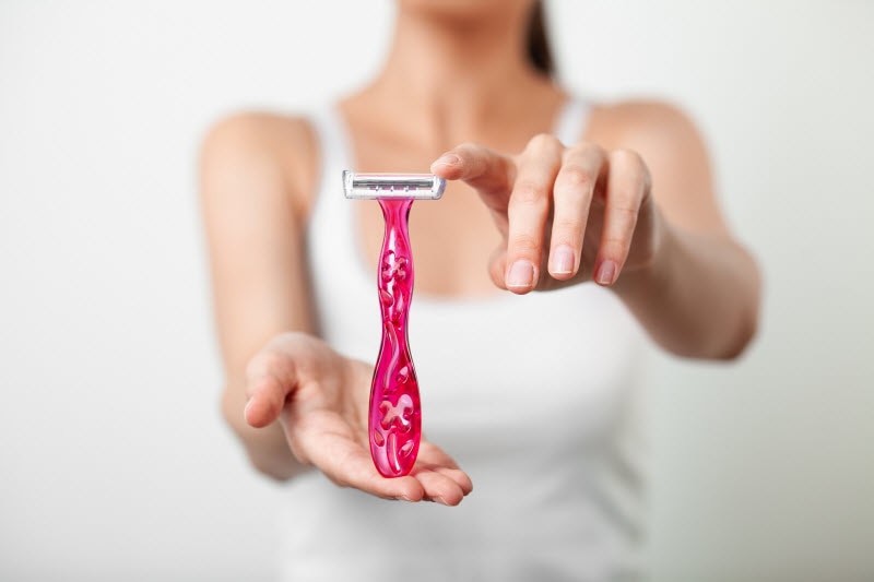 Focused View of Woman's Hands Holding Pink Razor to Represent Concept of Body Hair Removal Choice